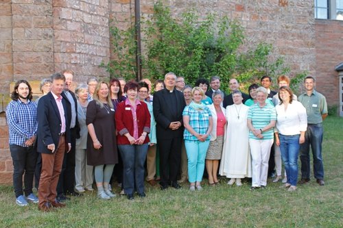 Bischof Wiesemann und eine Gruppe von Frauen und Männern der Pfarrei Franz von Assisi in Queidersbach stehen auf einer Rasenfläche.