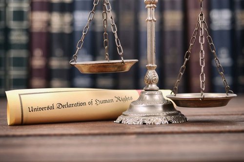 Eine alte Waage unter der ein Blatt mit dem Titel "Human rights", Menschenrechte, liegt.