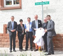 Gruppe von Männern und Frauen mit Weihbischof Otto Georgens vor dem Schild des neu eingeweihten Ernst-Gutting-Platzes in Landau